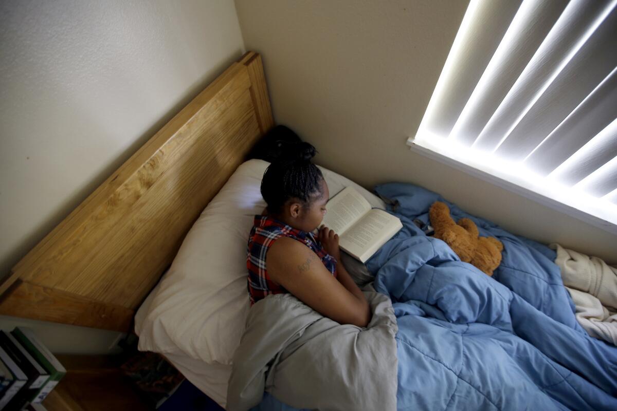 Diamond Hyman, 19, reads in her bed at the David and Margaret Youth and Family Services transitional shelter care facility for teenage girls in La Verne.