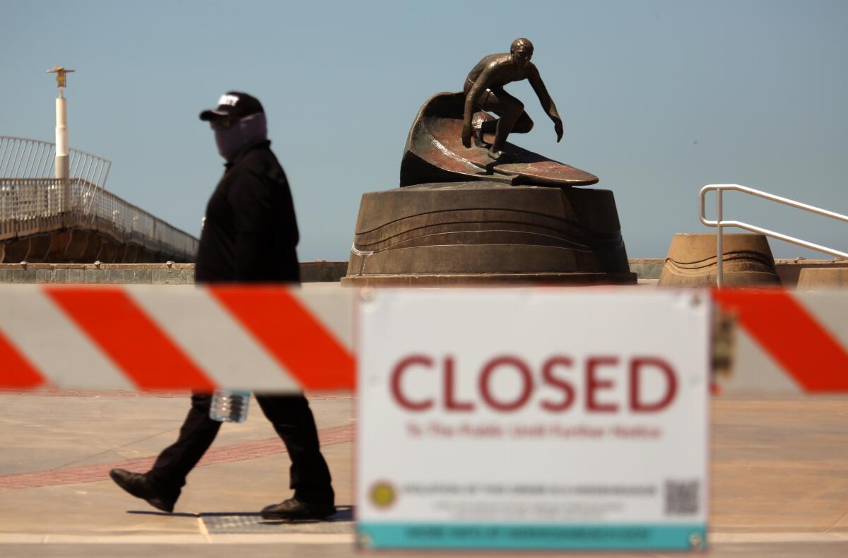A security guard walks by a statue of surfer Dewey Weber April 23 as he patrols the Strand in Hermosa Beach.