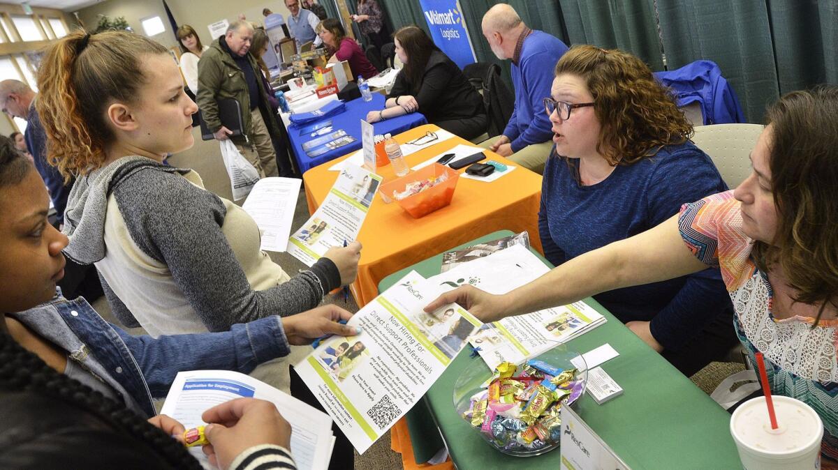 Kim Wesley, area supervisor for ResCare Residential Services, right, and Rhonda Purvis, a staff member, talk with job seekers at a job fair in Marion, Ind.