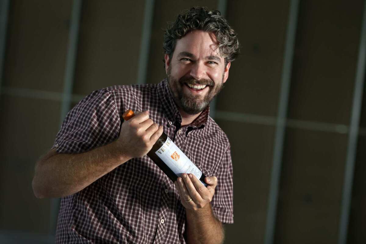 Kyle Meyer holds one of two bottles of wine he had on hand at his soon to be opened business in Santa Ana.