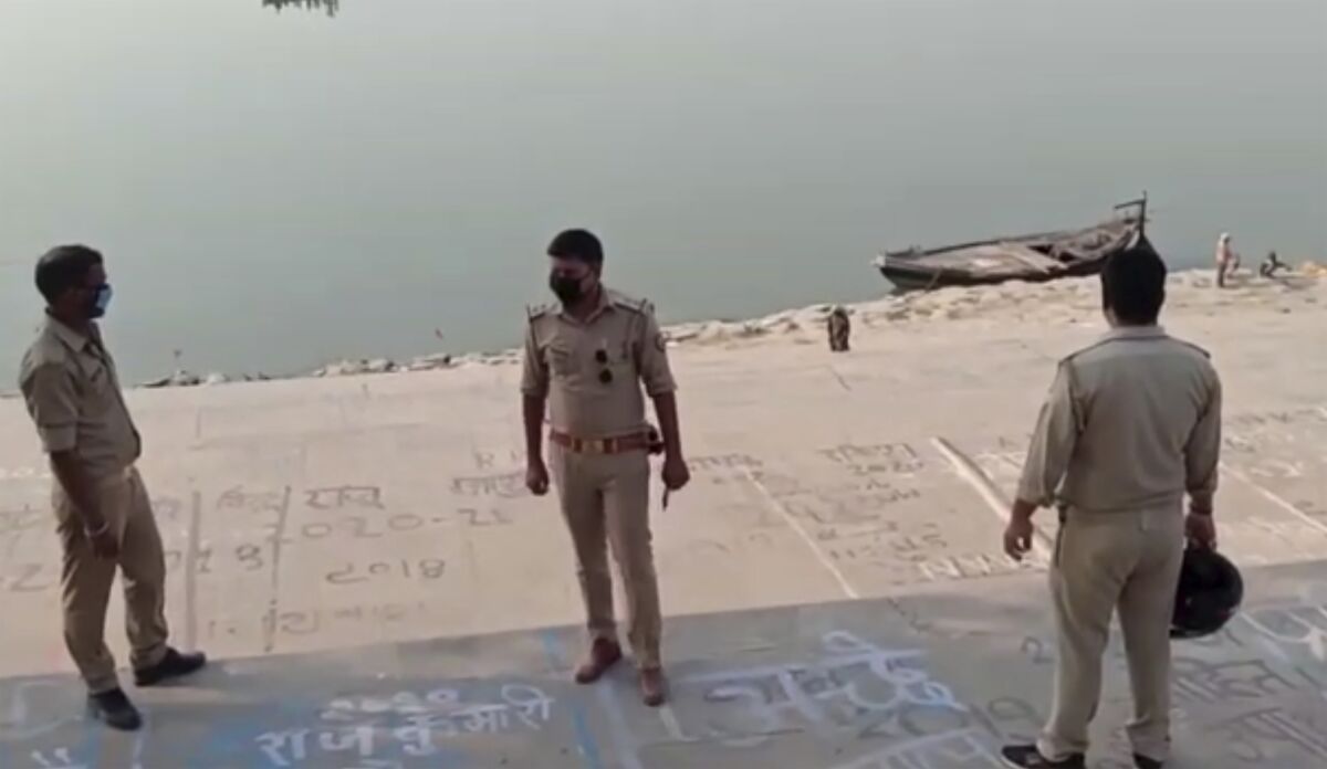 This frame grab from video provided by KK Productions shows police officials stand guard at the banks of the river where several bodies were found lying in Ghazipur district in Uttar Pradesh state India, Tuesday, May 11, 2021. Scores of dead bodies have been found floating down the Ganges River in eastern India amid a ferocious surge in coronavirus infections in the country, but authorities said Tuesday they haven't been able to determine the cause of death. Health officials working through the night Monday retrieved 71 bodies, officials in Bihar state said. (KK PRODUCTIONS via AP)