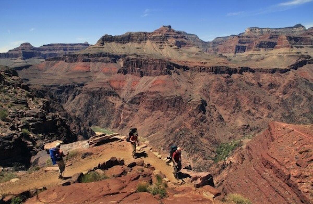 Hikers in Grand Canyon National Park walk along the South Kaibab Trail with the Colorado River below.
