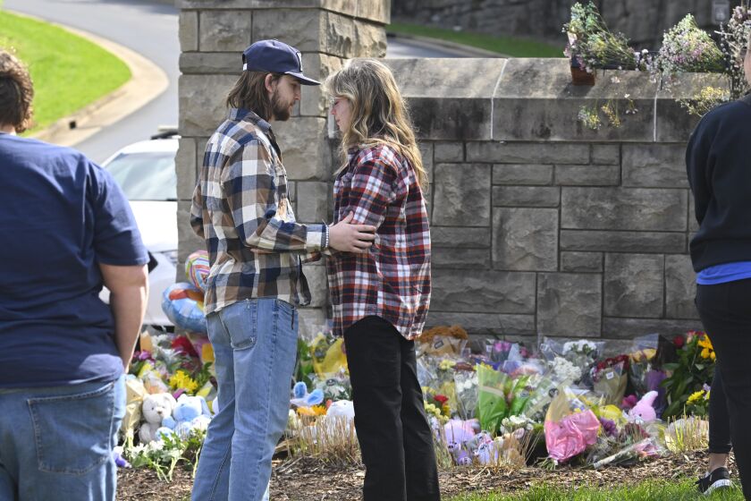People console each other at an entry to Covenant School, Tuesday, March 28, 2023, in Nashville, Tenn., which has become a memorial to the victims of Monday's school shooting. (AP Photo/John Amis)