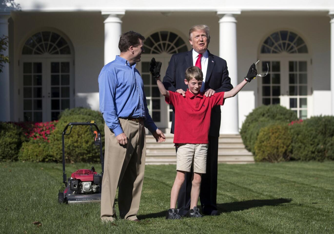 El presidente de Estados Unidos, Donald Trump (d) junto a Frank Giaccio (c), el hijo de Greg Giaccio (i), en el jardín de la Casa Blanca. Trump aceptó la oferta del pequeño de cortar el césped de la Casa Blanca.
