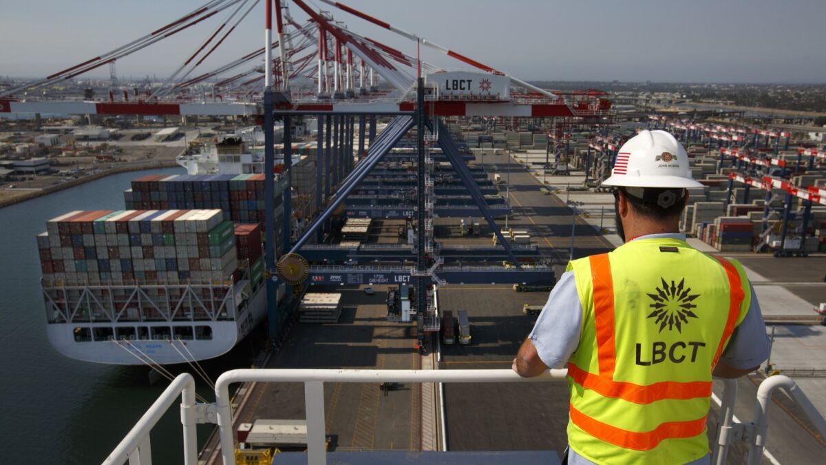 A worker with the Long Beach Container Terminal watches a container ship being unloaded.