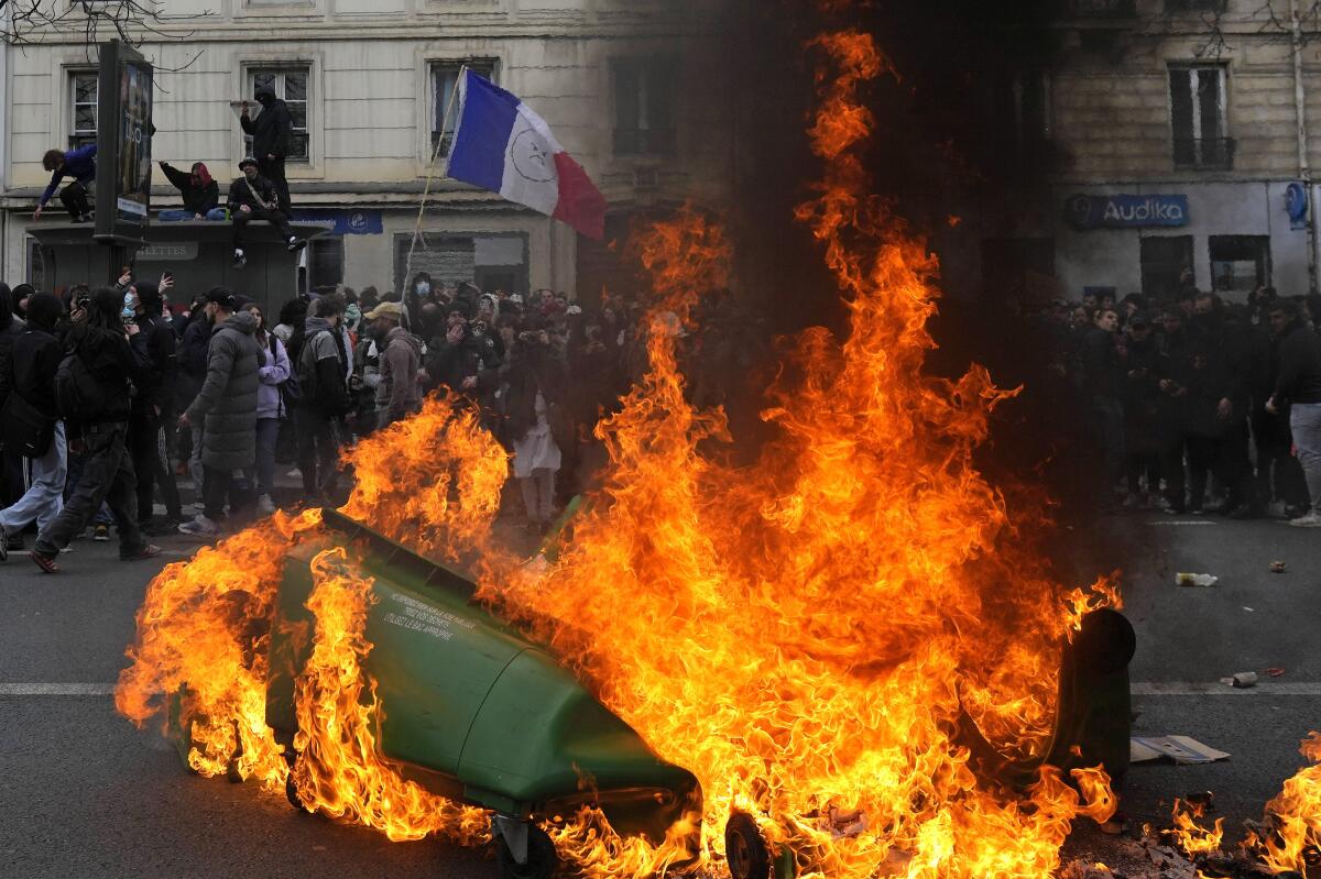 Protesters walking past burning garbage cans in Paris