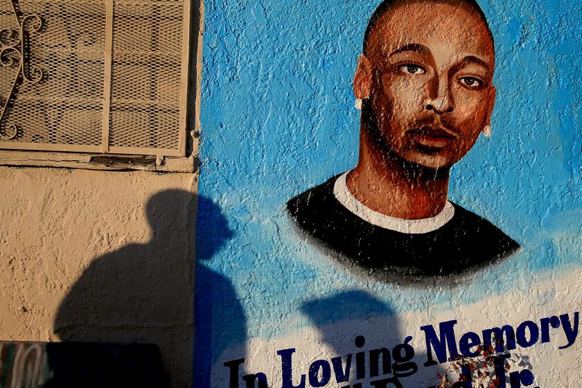 Passersby pause at a memorial to Ezell Ford, who was shot and killed by the LAPD last summer.
