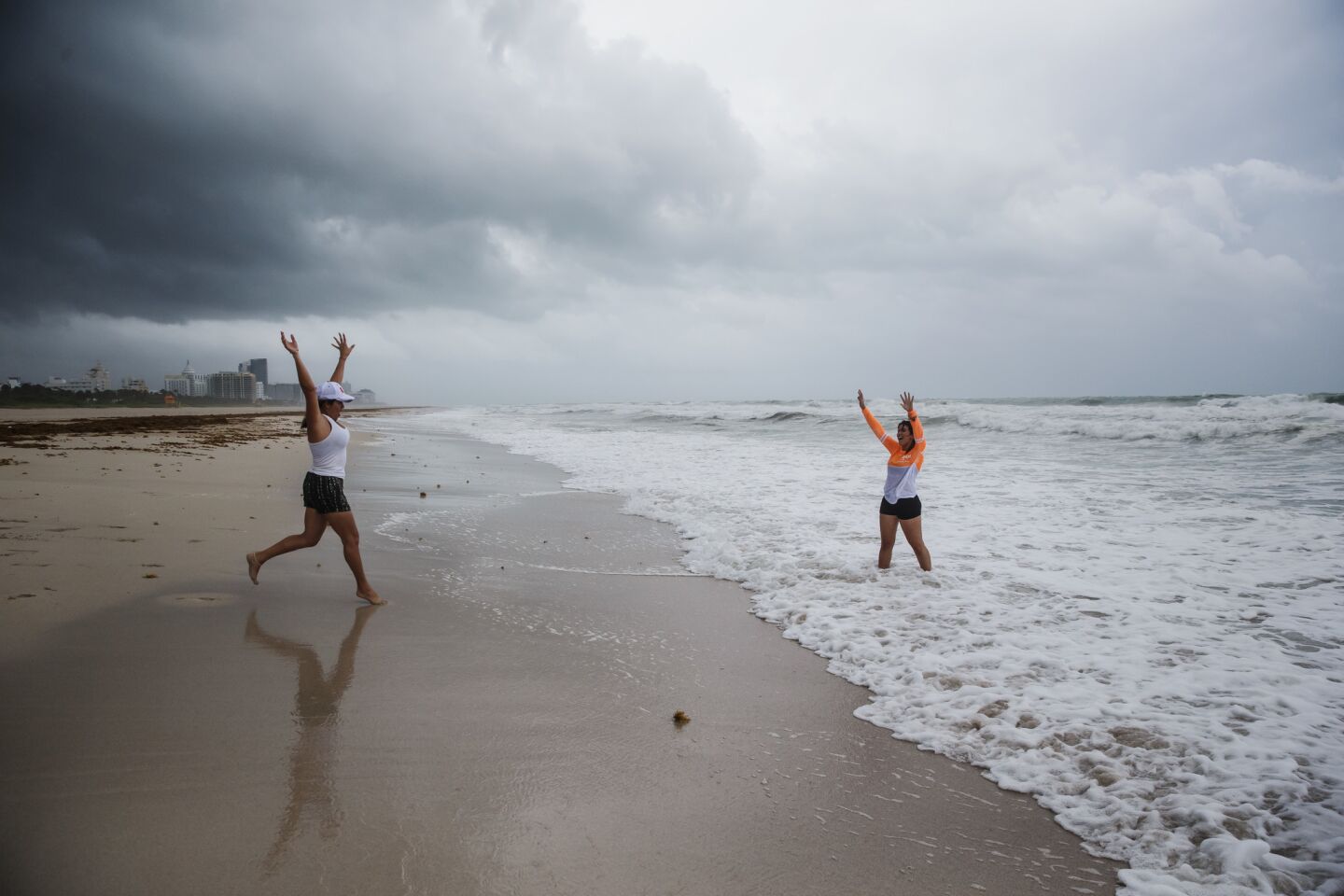 Lisette Toroella and Tatiana Morera play on the beach as storm clouds approach in Miami Beach.