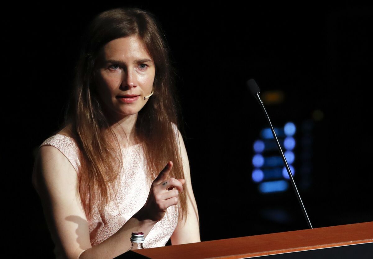 Amanda Knox points while speaking at a lectern