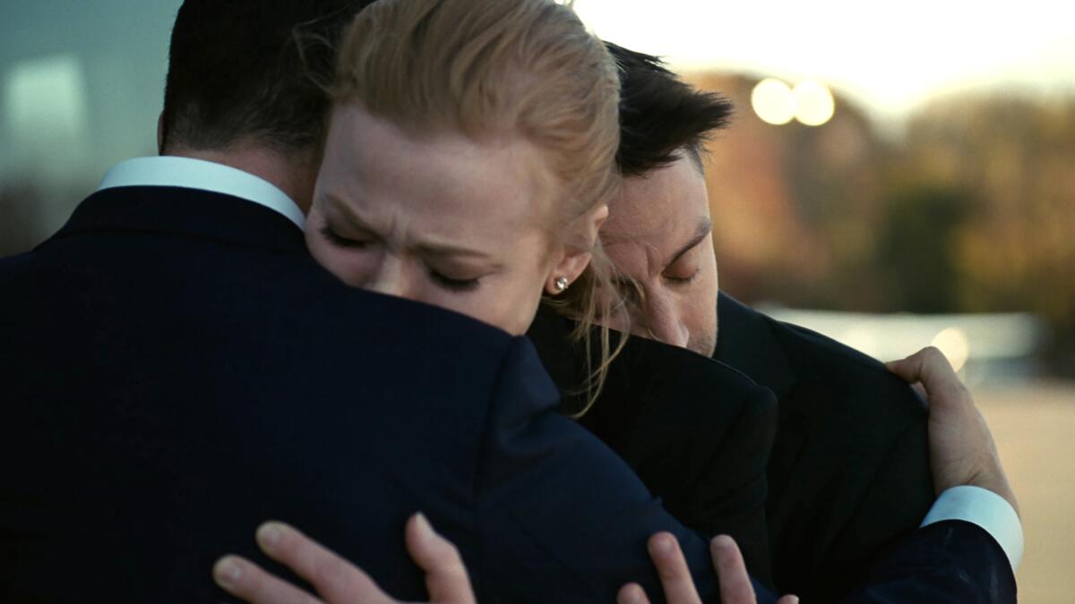 A woman and two men embrace