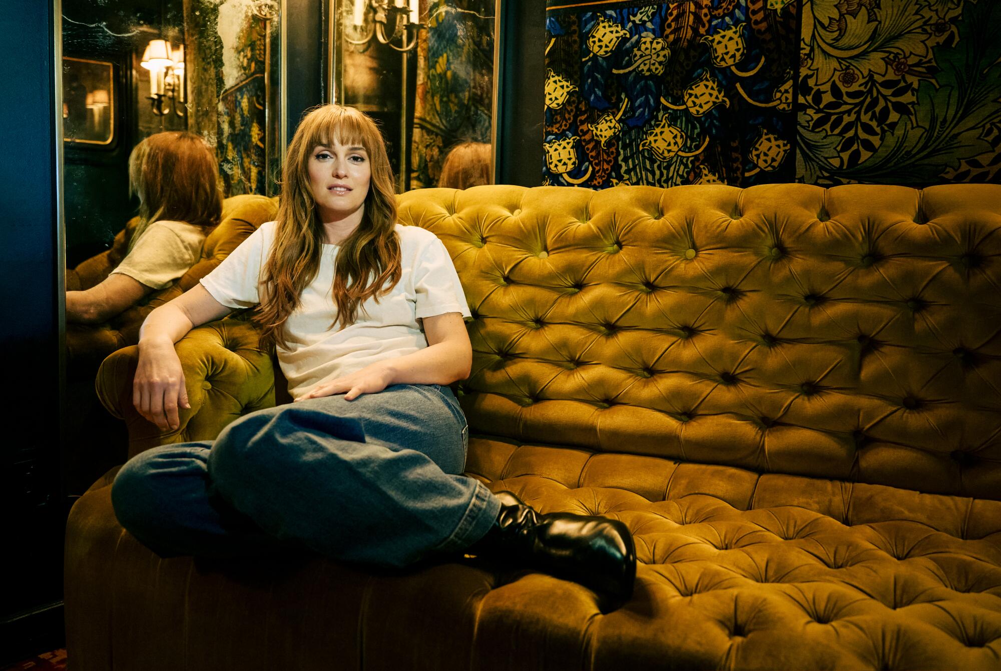 A pistillate with agelong hairsbreadth sits casually, legs up, connected a golden quilted sofa
