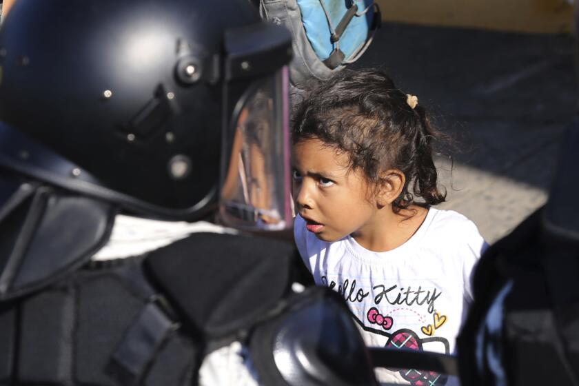 Una niña encara a un efectivo de la guardia nacional mexicana en el cruce fronterizo entre Guatemala y México en Tecún Umán, Guatemala, sábado 18 de enero de 2020. (AP Photo/Marco Ugarte)