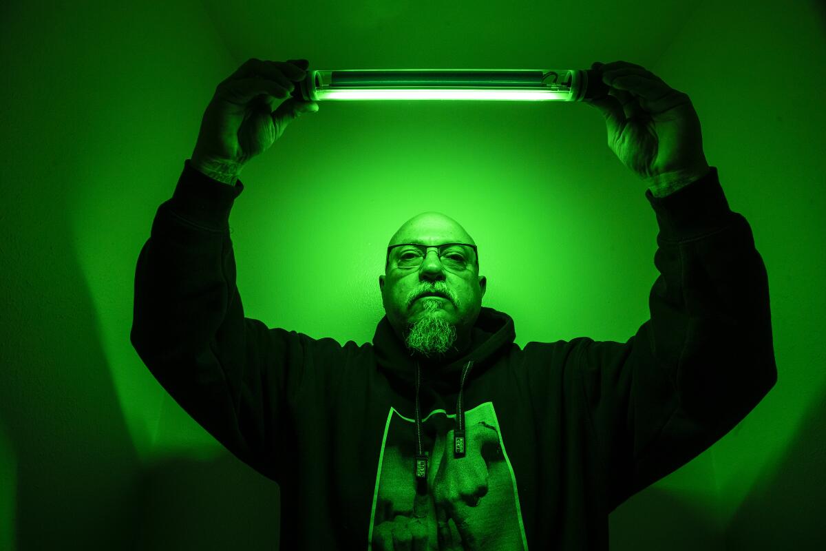A man in a hoodie holds up a portable light.