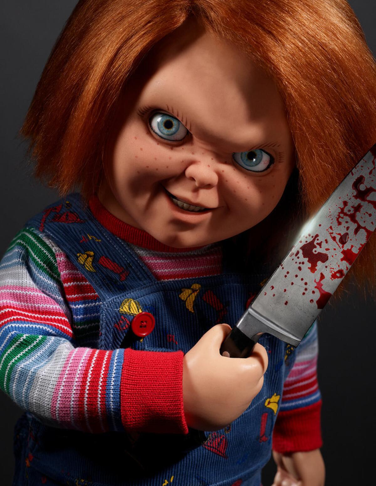 Chucky, the killer "Child's Play" toy, smiling and holding a bloodied knife next to his face