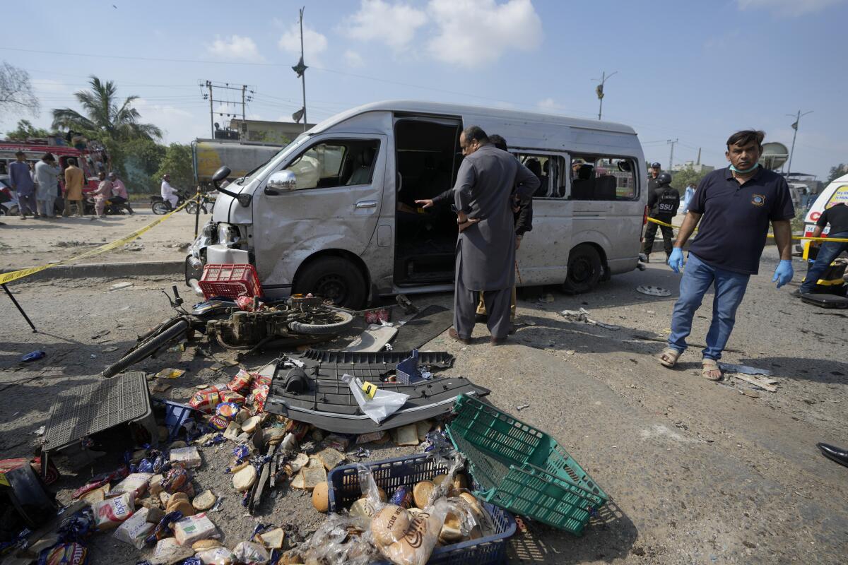 Pakistani investigators examine a damaged van at the site of a suicide attack.