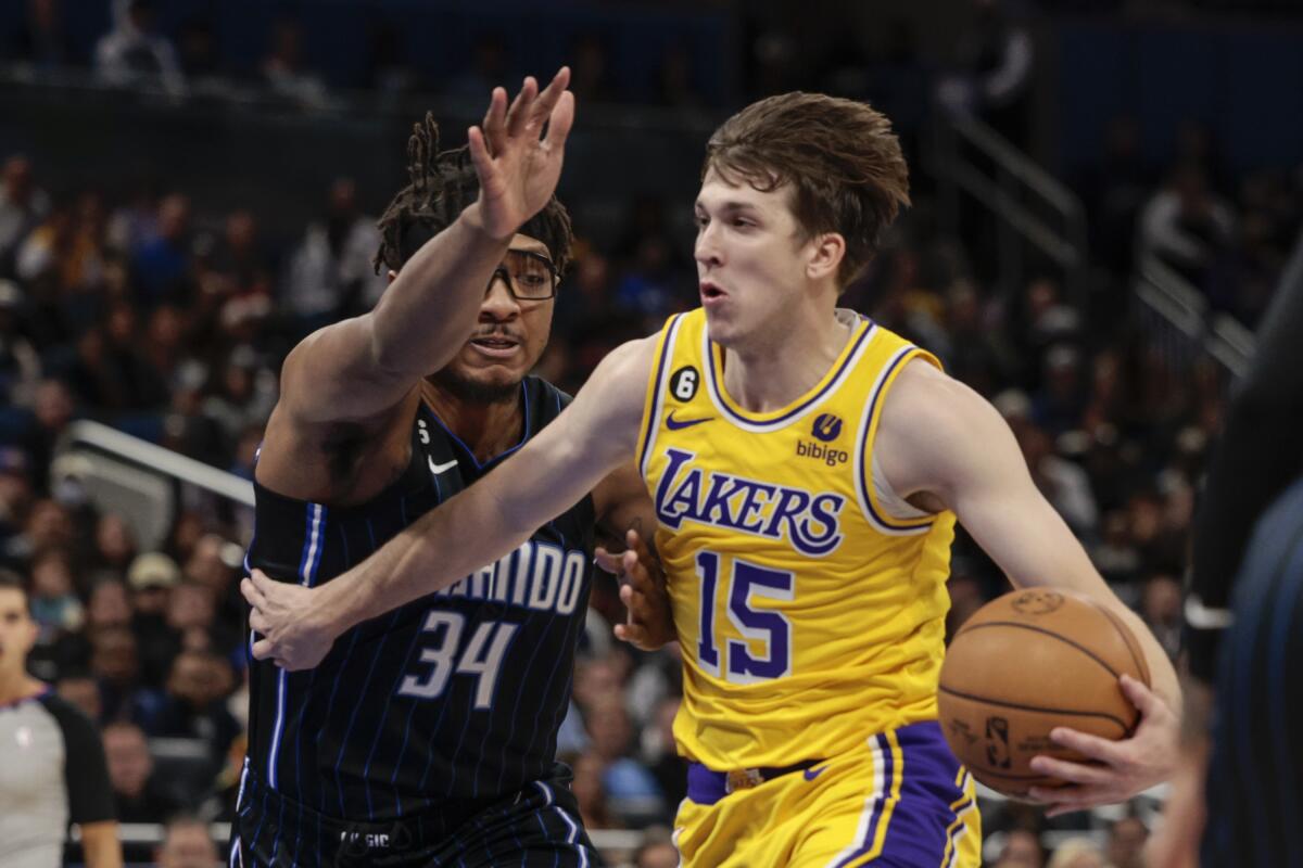 Austin Reaves tries to drive past a Magic player.