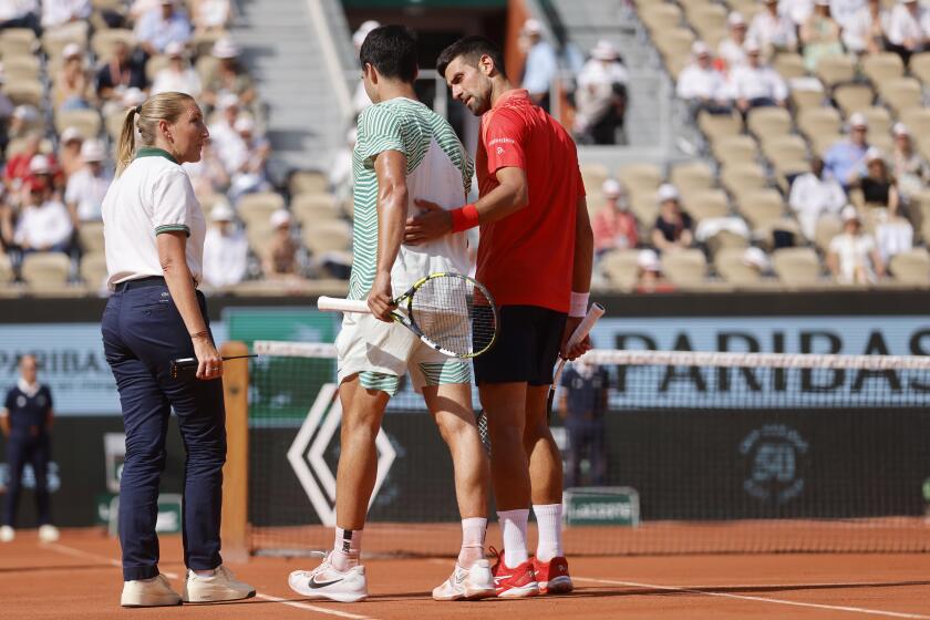Spain's Carlos Alcaraz, center, walks with the help of Serbia's Novak Djokovic, right, as he is injured during their semifinal match of the French Open tennis tournament at the Roland Garros stadium in Paris, Friday, June 9, 2023. (AP Photo/Jean-Francois Badias)