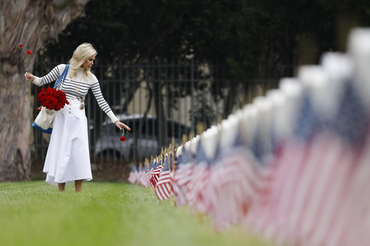 A woman dropping carnations in front of headstones