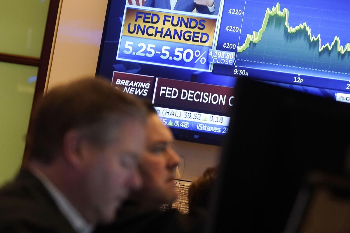 A TV screen shows the rate decision of the Federal Reserve as traders work on the floor of the New York Stock Exchange.