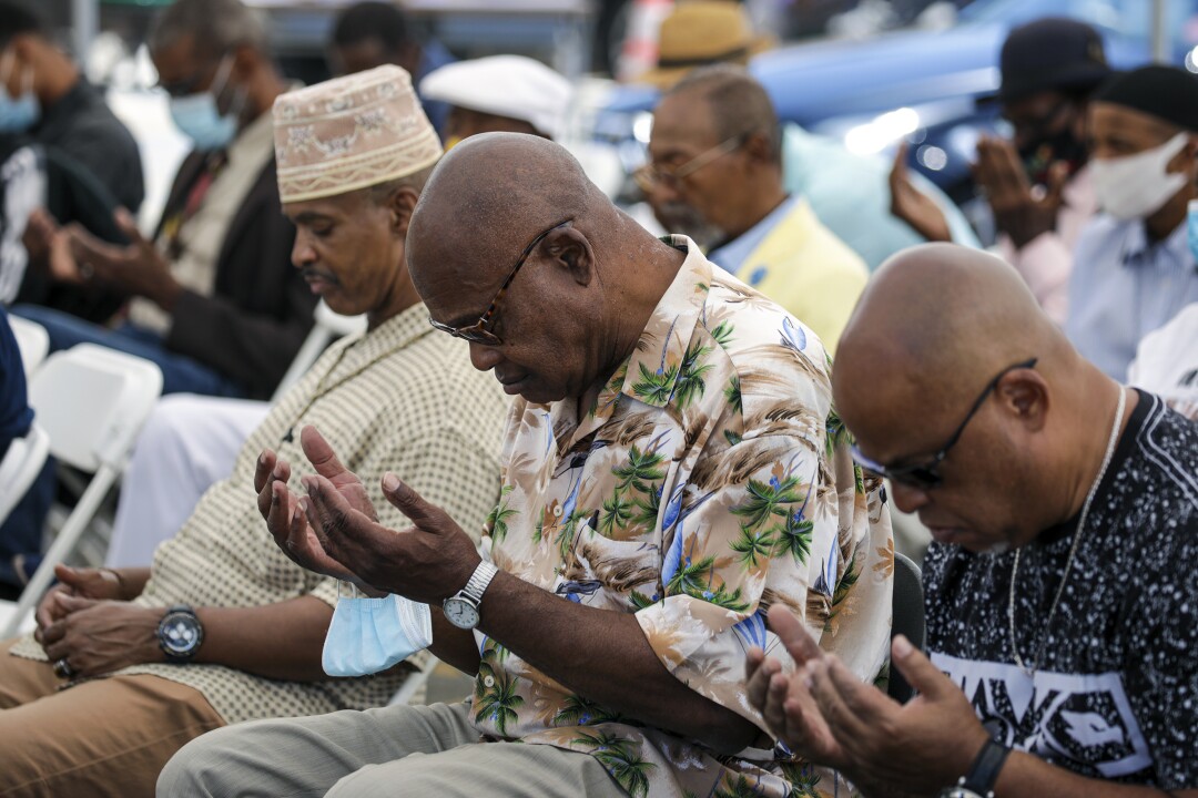 Men sit with their heads bowed in prayer