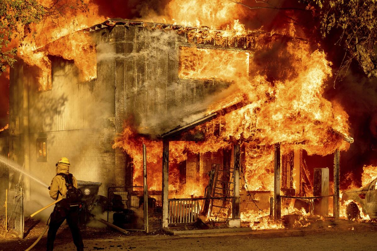 A firefighter sprays water while a home burns