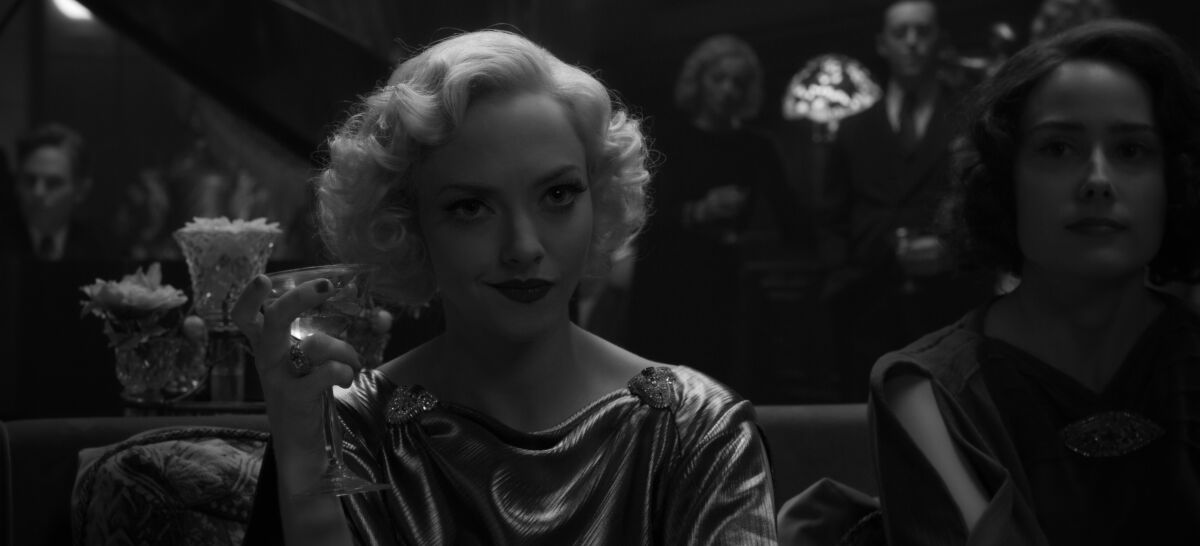 Amanda Seyfried, in period garb, raises a glass in "Mank."