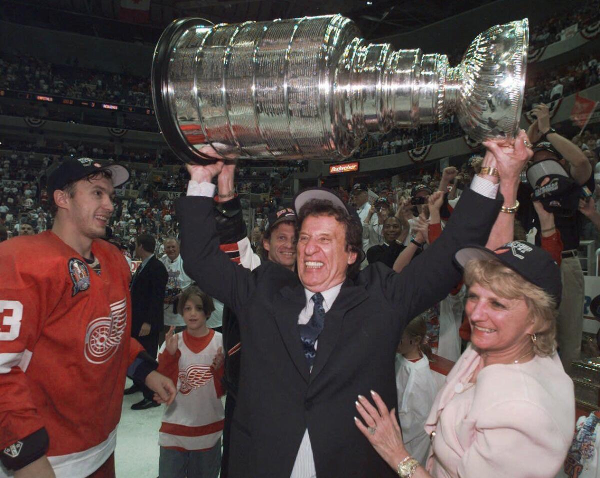 Detroit Red Wings owner Mike Ilitch, center, hoists the Stanley Cup in Washington after his team won its second consecutive NHL championship in 1998.