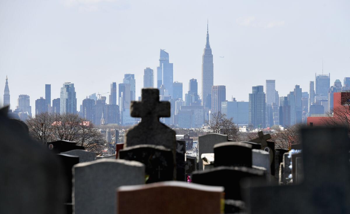 Gravestones from a cemetery are seen with the Manhattan skyline