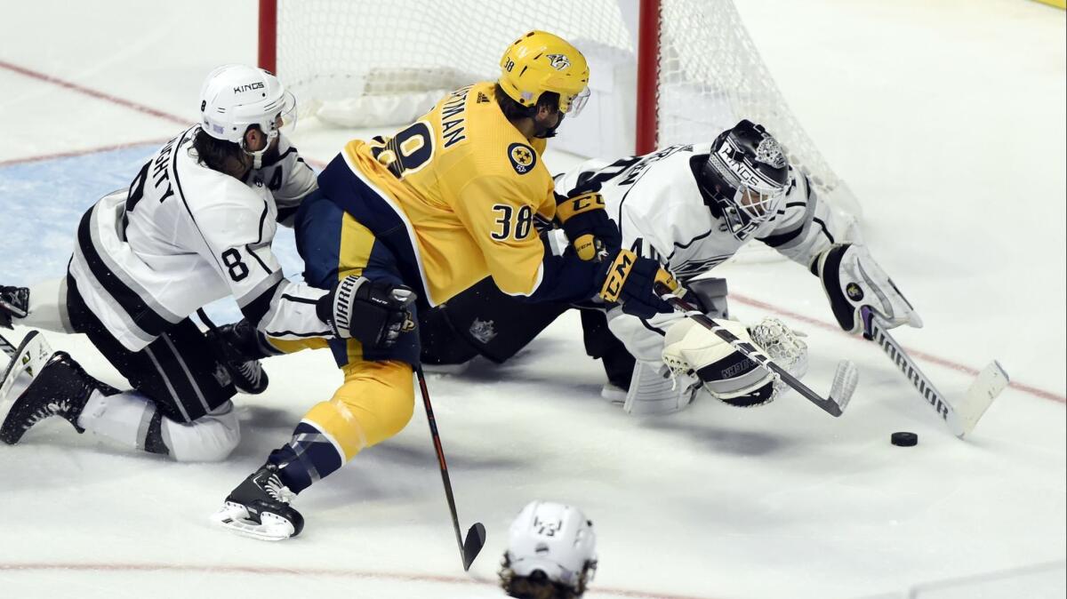 Kings goalie Calvin Petersen reaches for the puck in front of teammate Drew Doughty and Nashville's Ryan Hartman.