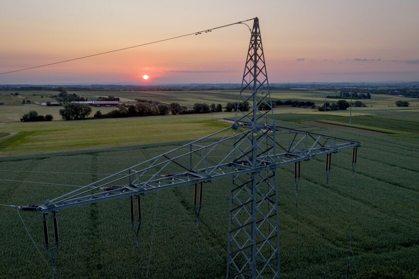 FILE - A transmission tower stands on a field in the outskirts of Frankfurt, Germany, as the sunrises on June 6, 2023. A report released Wednesday, June 7, 2023, by the International Energy Agency says that demand for energy is growing, yet emissions are not growing as fast. (AP Photo/Michael Probst, File)