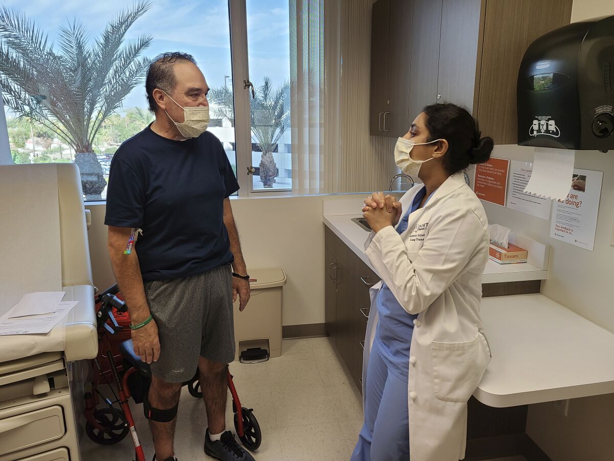 In this photo provided by Dignity Health St. Joseph's Hospital, Arthur Sanchez, left, speaks with Dr. Ashwini Arjuna during a follow-up appointment, post-transplant, at St. Joseph's Hospital in Phoenix, Wednesday, Oct. 21, 2020. Seven months after he was first hospitalized in his hometown of Las Cruces, New Mexico, with COVID-19, the 52-year-old utility worker has a brand new set of lungs. (Courtesy of Dignity Health St. Joseph's Hospital via AP)