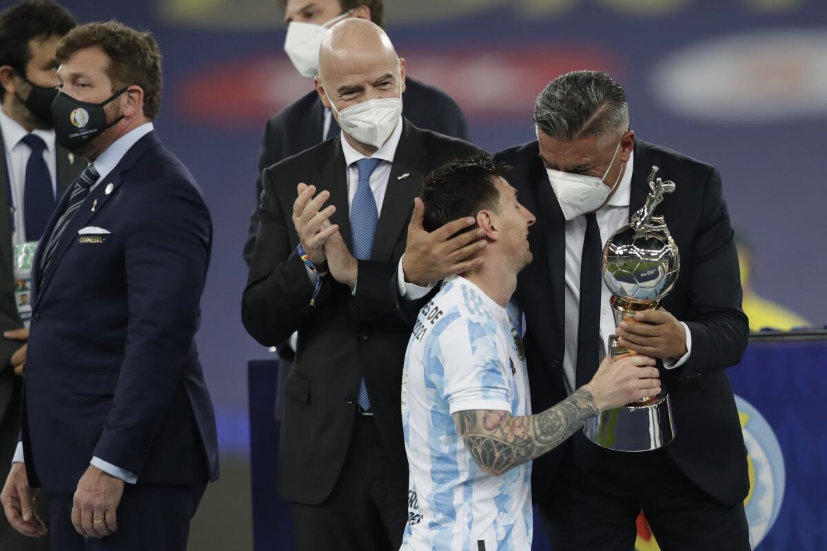 Argentine Football Association, (AFA) President Claudio Tapia, right, gives the trophy for the best player to Argentina's Lionel Messi during the award ceremony after defeating Brazil 1-0 in Copa America final soccer match at Maracana stadium in Rio de Janeiro, Brazil, Saturday, July 10, 2021. (AP Photo/Andre Penner)