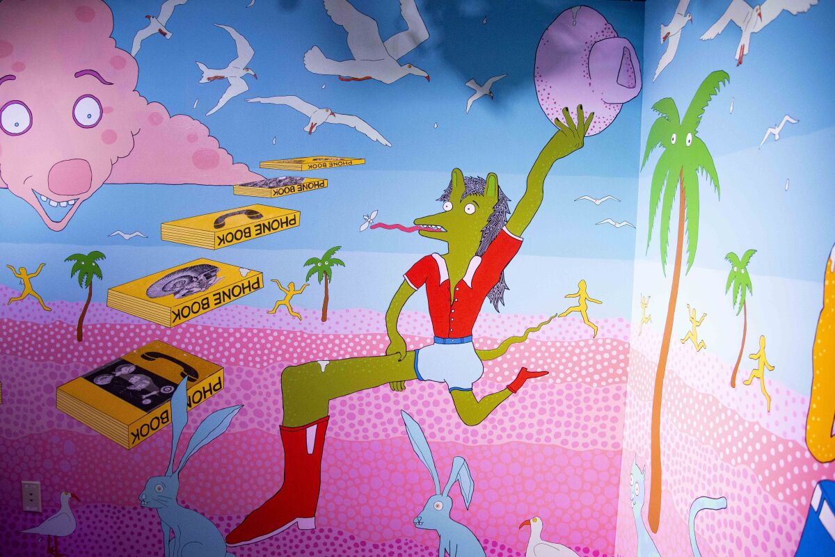 A green creature holding a pink cowboy hat is painted onto a mural.