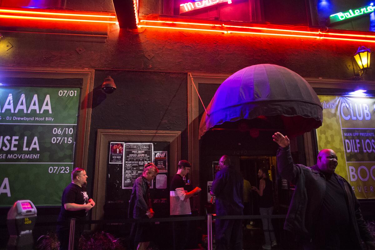 People line up to enter Los Globos at night, with a bouncer waving outside.