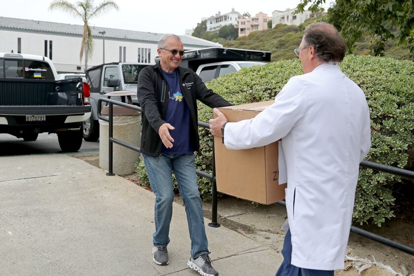 SAN CLEMENTE, CA - June 2: Ukrainian American Daniel Bondarenko, left, 65, of Mission Viejo accepts a box packed with surgical supplies from Orthopaedic surgeon Dr. Gus Gialamas at Sea View Orthopaedic Medical Group on Wednesday, June 2, 2022 in San Clemente, CA. (Kevin Chang / Daily Pilot)