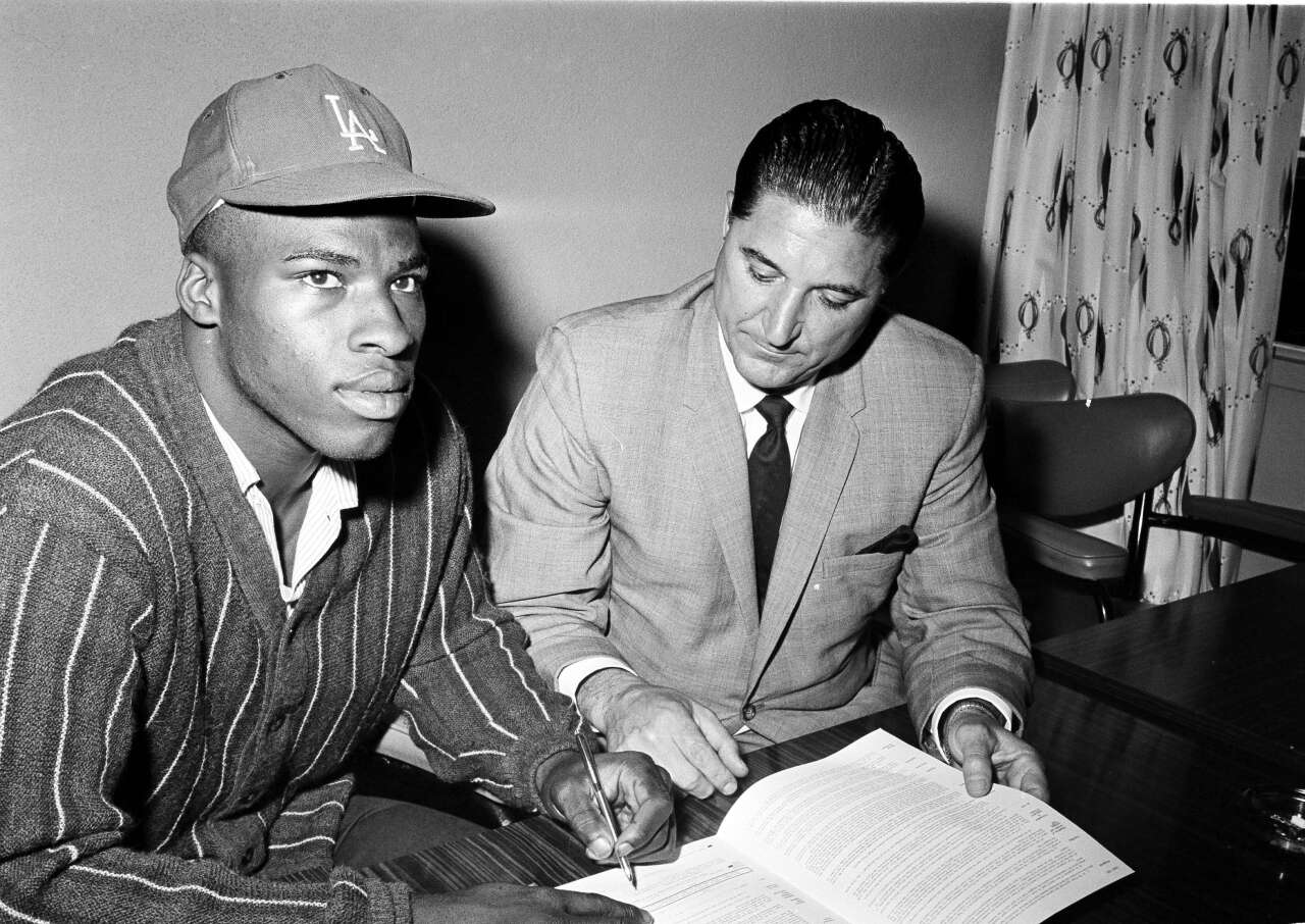 Willie Crawford, 17, who hit .444 for Fremont High, signs a $100,000 deal with the Dodgers in 1964 as Al Campanis watches.