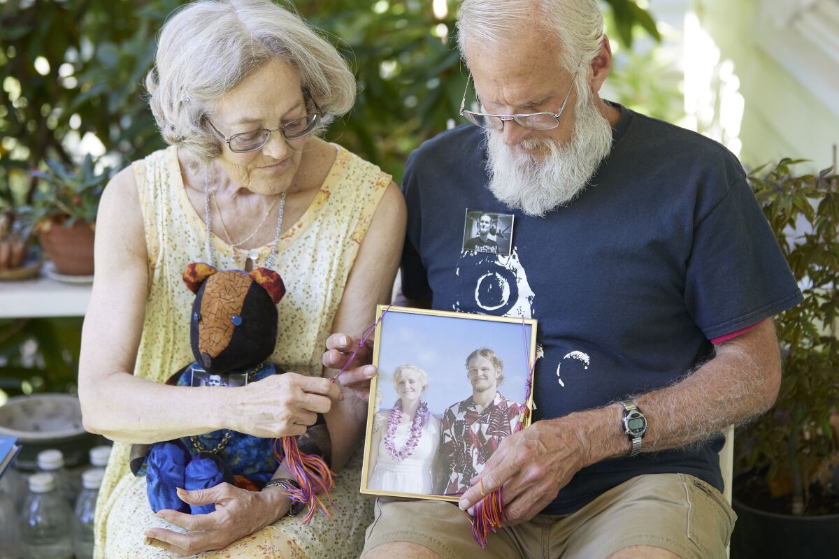 George, right, and Carolyn Spaulding hold an old family photo showing their son, Brian, in Portland, Ore., Wednesday, July 20, 2022. Five years after Brian's parents found him fatally shot in the home he shared with roommates, his slaying remains a mystery that seems increasingly unlikely to be solved as Portland police confront a spike in killings and more than 100 officer vacancies. (AP Photo/Craig Mitchelldyer)
