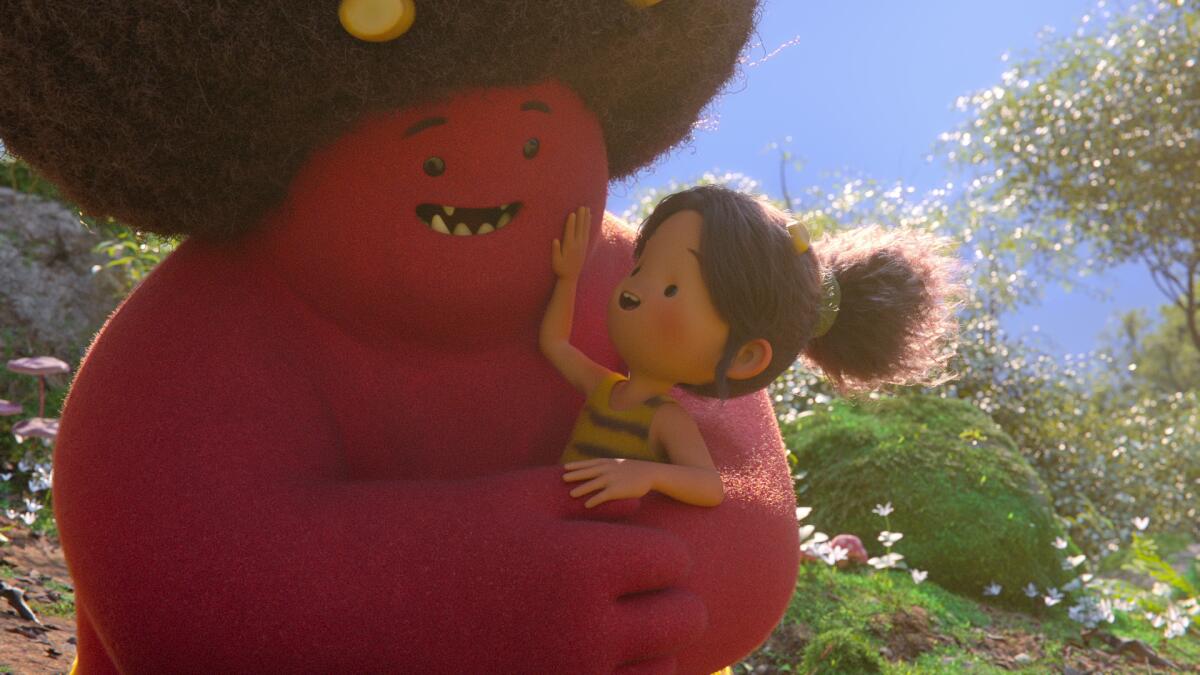 A young girl in the arms of a cuddly red monster with an Afro.