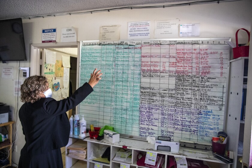 A woman gestures toward a large whiteboard covered in color-coded notes