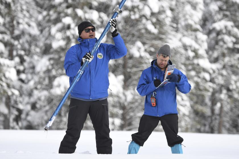 In this photo provided by the California Department of Water Resources, forecasting chief Sean de Guzman left, and engineer Andy Reising work the measurement phase of the first media snow survey of the season at Phillips Station in the Sierra Nevada Mountains, Calif., Tuesday, Jan. 3, 2023. The snowpack in California's mountains is off to one of its best starts in 40 years, officials announced Tuesday, offering hope that the drought-stricken state could soon see relief in the spring when the snow melts and flows into reservoirs that provide water for drinking and farming. (Kenneth James/California Department of Water Resources via AP)