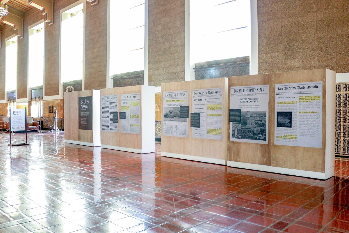 An installation view of "Broken News" shows vintage news clips adhered to a series of wood panels