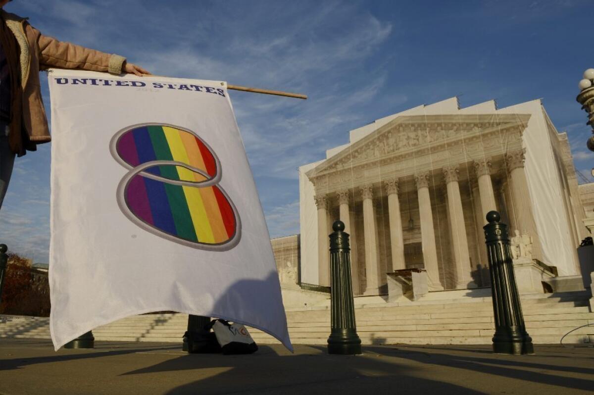 A supporter of same-sex marriage holds a flag that depicts two wedding bands outside the Supreme Court in Washington on Nov. 30.
