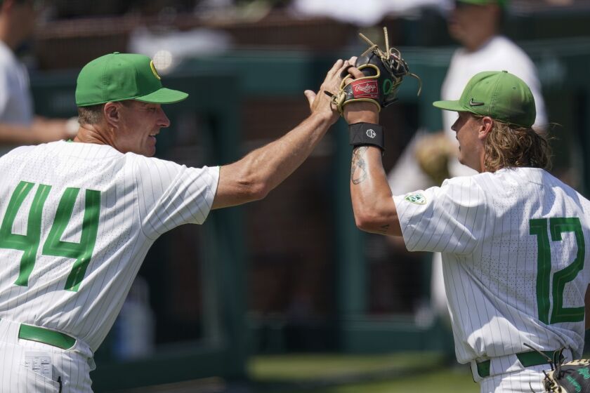 Oregon head coach Mark Wasikowski congratulates pitcher Matt Dallas (12) as he comes off the field after pitching against Xavier during the eighth inning of an NCAA college baseball tournament regional game Friday, June 2, 2023, in Nashville, Tenn. (AP Photo/George Walker IV)