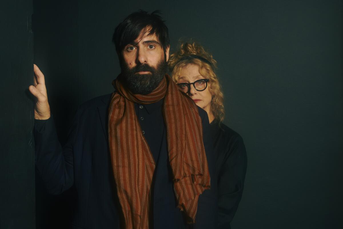 Jason Schwartzman stands in front of Carol Kane, who looks over his shoulder.