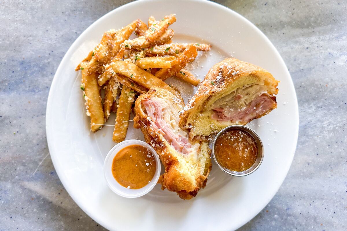 The Monte Cristo — a battered and fried sandwich with sliced turkey, ham and Swiss cheese — served with sauces and fries