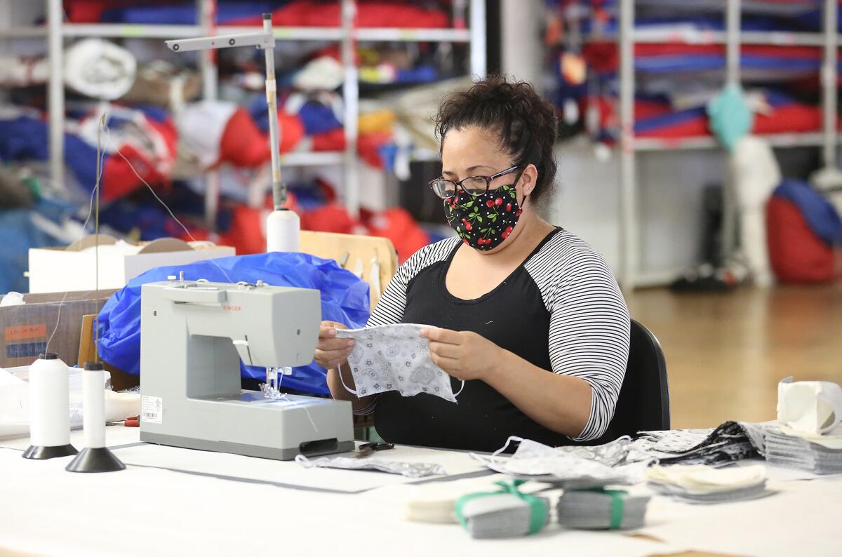 Gabriela Garcia sews the second part of a face covering at the Ullman Sails Newport Beach workshop in Santa Ana.