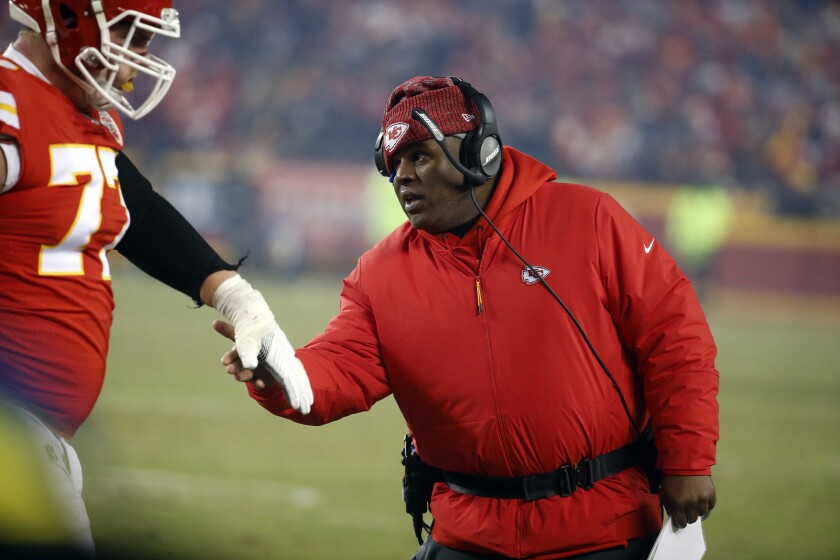 FILE - In this Jan. 20, 2019, file photo, Kansas City Chiefs offensive coordinator Eric Bieniemy greets a player during the second half of the team's AFC championship NFL football game against the New England Patriots in Kansas City, Mo. One year ago, Bieniemy and San Francisco 49ers defensive coordinator Robert Saleh missed out on the coaching carousel despite being coordinators of the two Super Bowl teams. The two figure to be near the top of many of the lists of possible head coaching candidates again this offseason when the NFL is hoping some new rules lead to more opportunities for minority coaches. (AP Photo/Charlie Riedel, File)