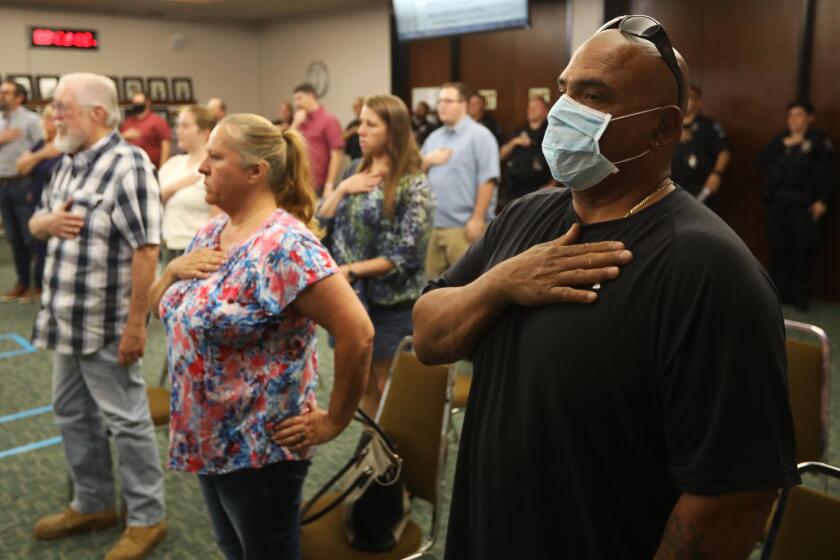 ATWATER, CA - MAY 26, 2020 - - Randy Romero, one of the few wearing a mask to prevent COVID-19, says the Pledge of Allegiance at the start of the weekly Atwater City Council meeting in Atwater on May 26, 2020. The city of Atwater in Merced County has declared itself a "sanctuary city" from the state's stay-at-home orders and has been open for business for over a week now. (Genaro Molina / Los Angeles Times)