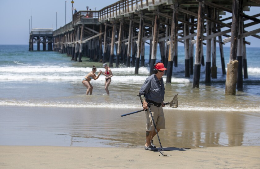 Stan Ross uses a metal detector near Newport Beach Pier on Wednesday.