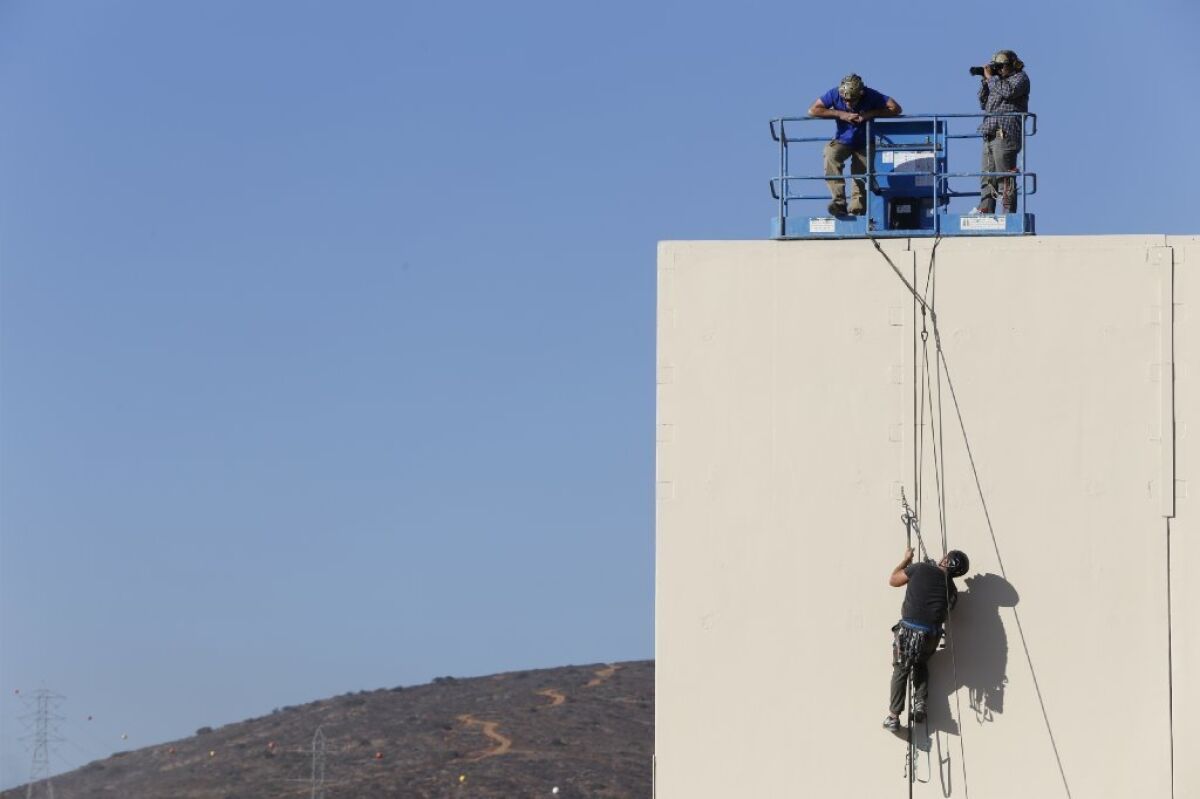 Tijuana, Baja California, Mexico December 1st, 2017 | Testing the border wall prototypes. A climber moves up the wall. This entry is built by: Caddell Construction Co., (DE) LLC Montgomery Alabama. Concrete.